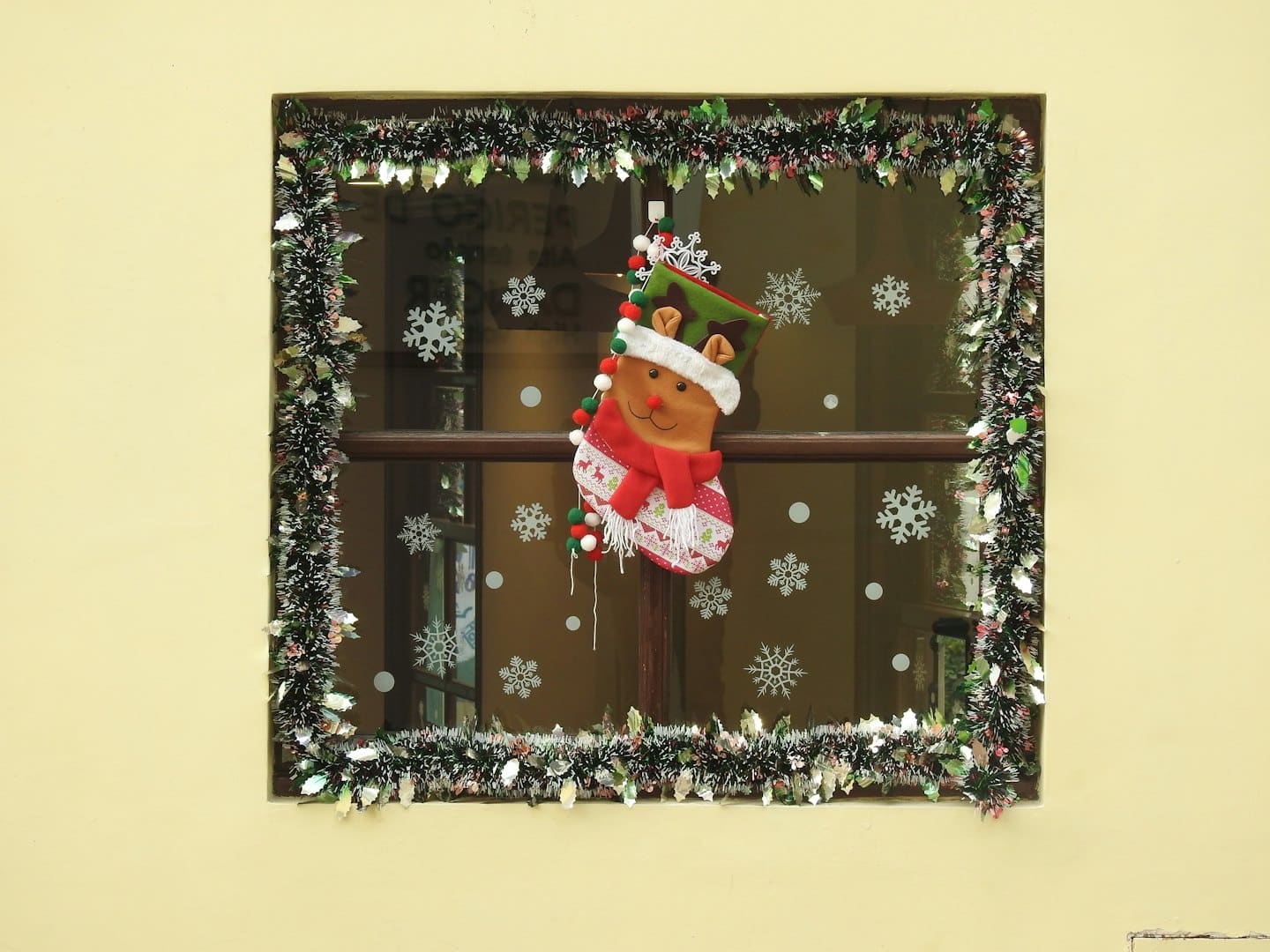 Christmas stocking hangs inside a window decorated with snowflakes.