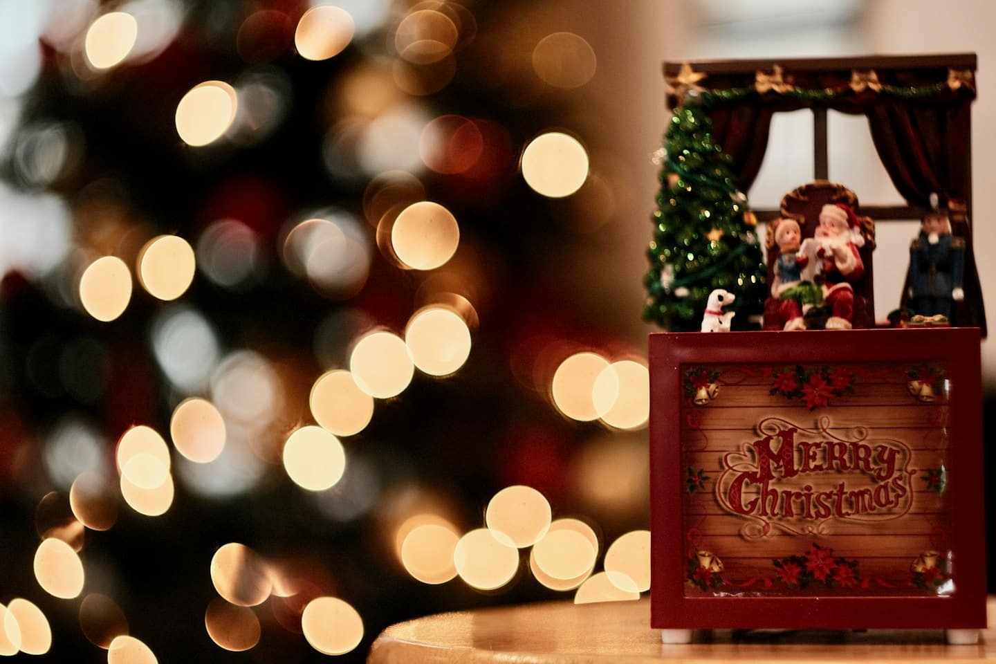 Christmas music box with Santa and child beside tree.