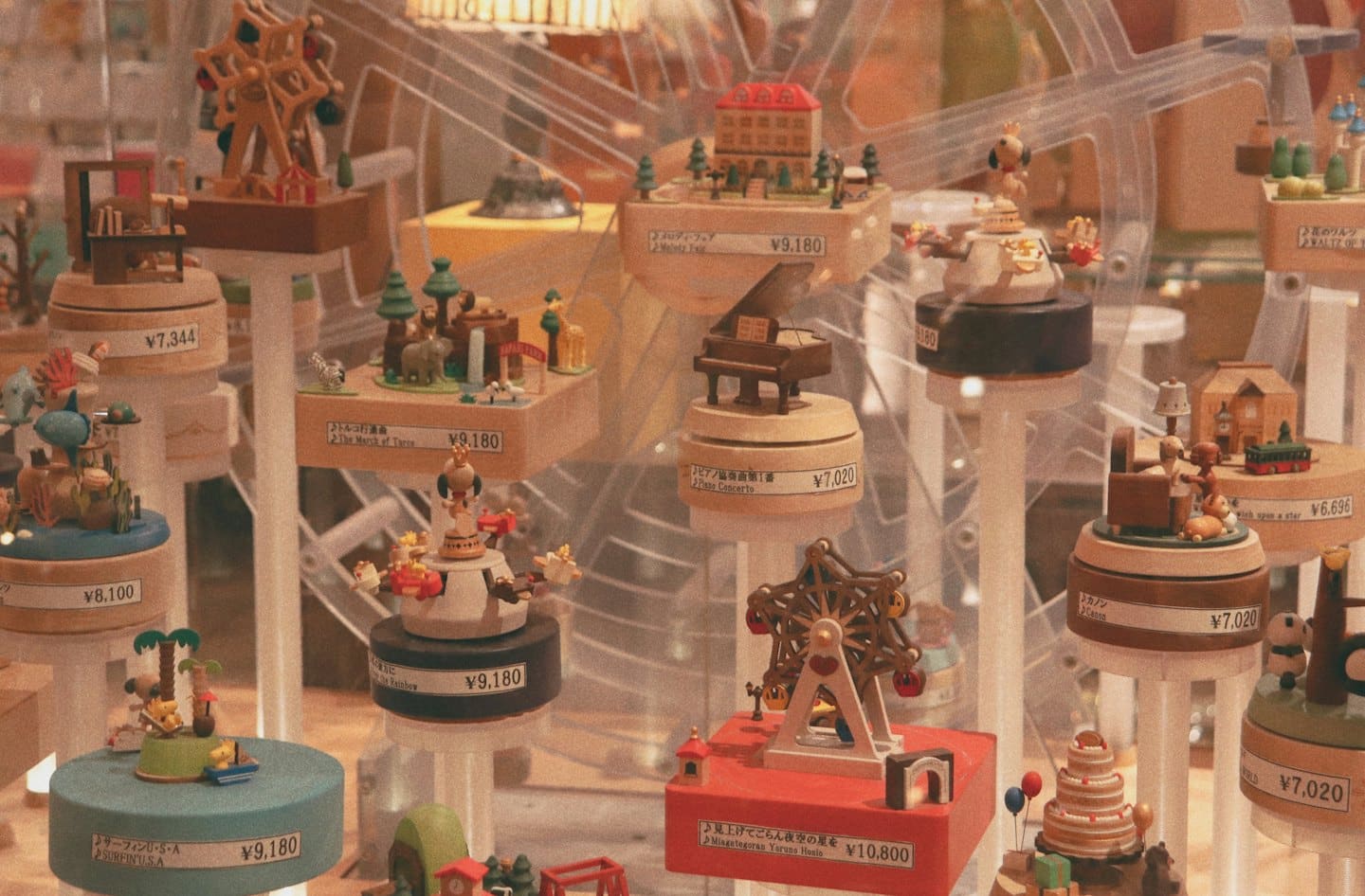 Intricate wooden music boxes displayed on white pedestals in a store.